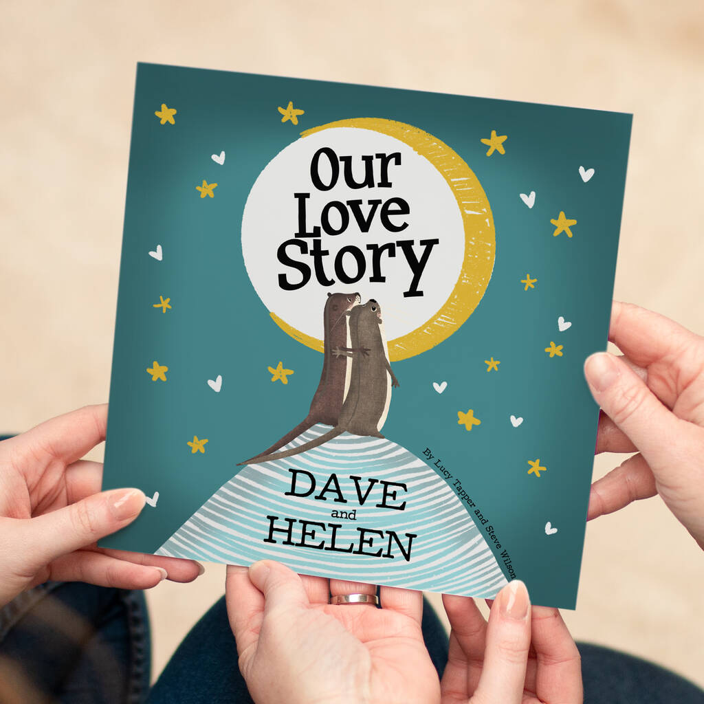 A personalised love story book titled 'Our Love Story' featuring an illustration of two otters cuddling under a moonlit sky, held by a couple—an ideal Valentine's Day gift.
