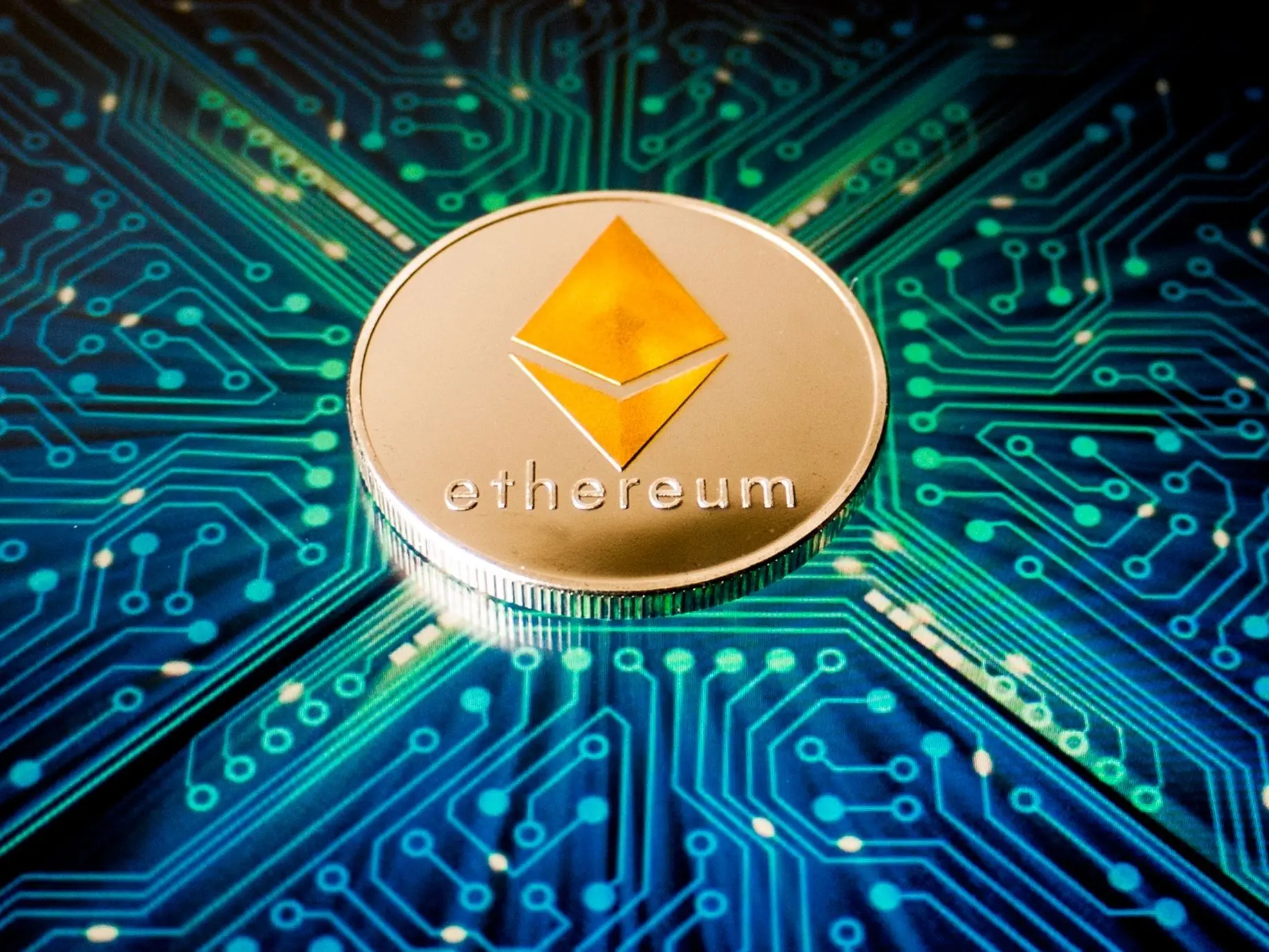 A physical Ethereum coin placed on a glowing blue digital circuit board, symbolising blockchain technology and decentralised finance.