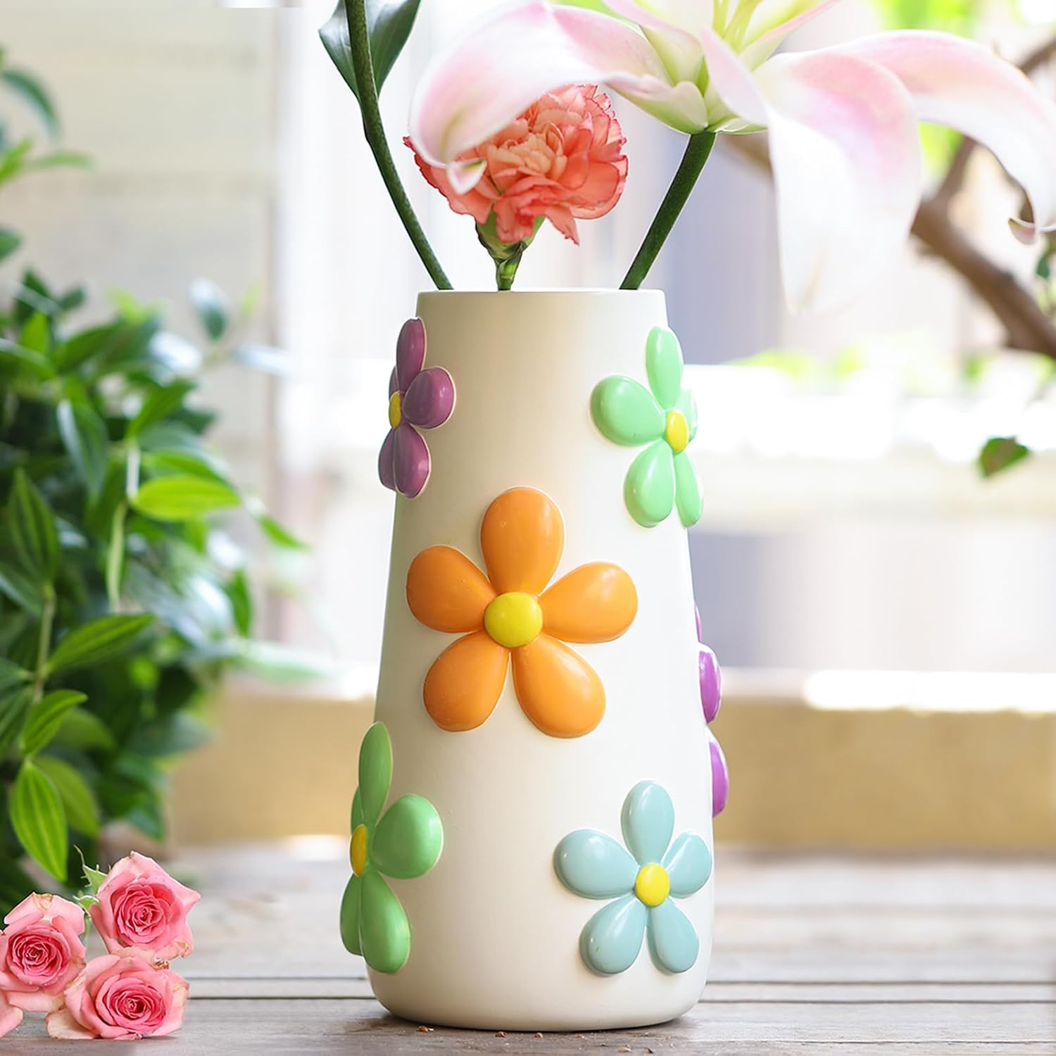 White ceramic vase decorated with colourful 3D daisy flowers in orange, purple, green, and blue.