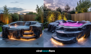 Stunning luxury outdoor rock formation hot tub with cascading water and LED lighting in a landscaped garden at dusk.