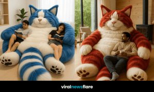 Giant fluffy red-and-white cat-shaped chair with man relaxing and holding a mug in a bright modern room.