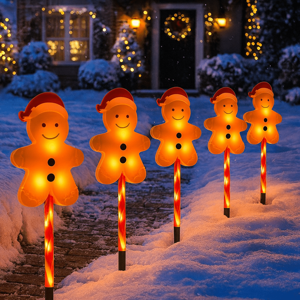 Glowing gingerbread man lights wearing Santa hats illuminating a snowy garden path