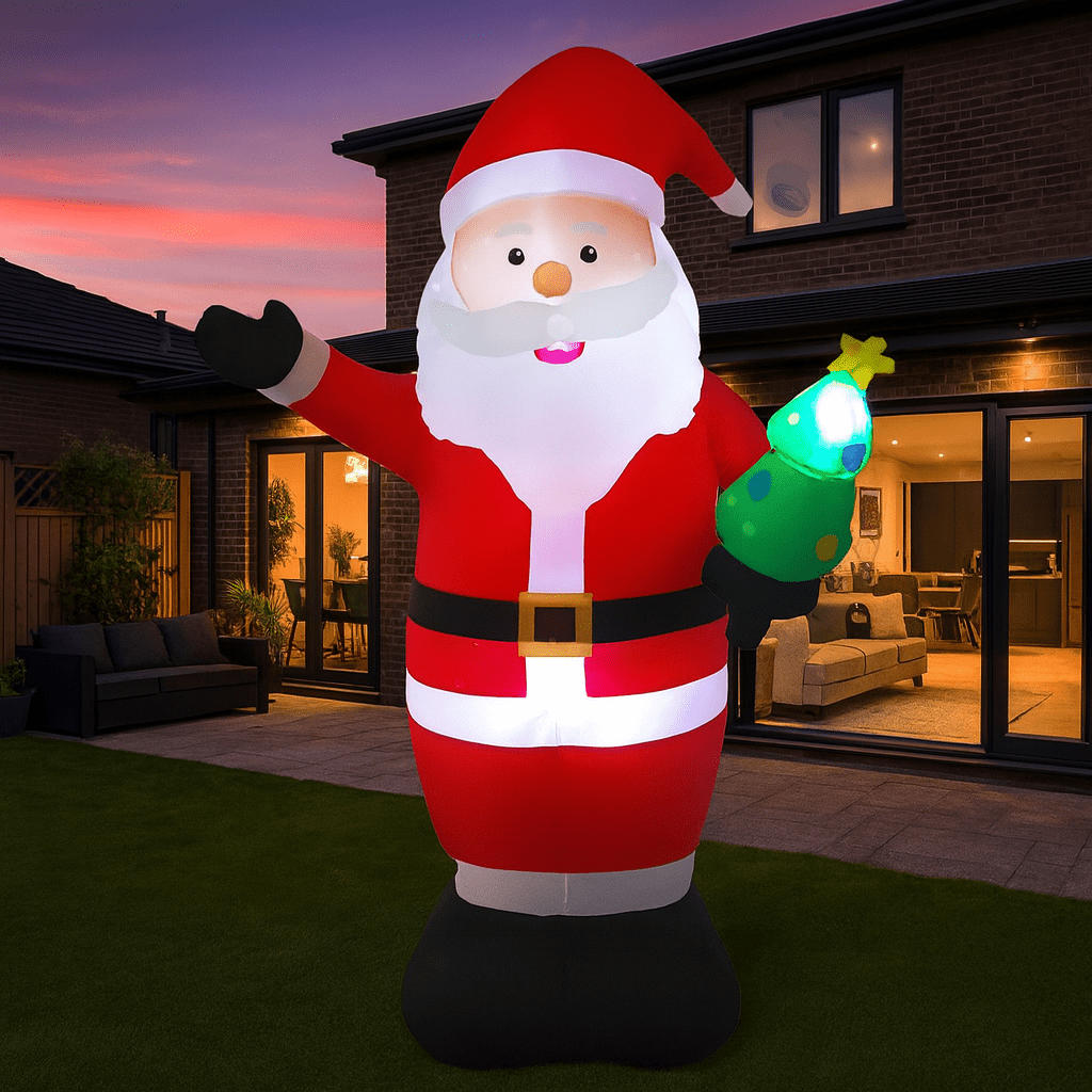Giant inflatable Santa Claus holding a glowing Christmas tree in a contemporary garden