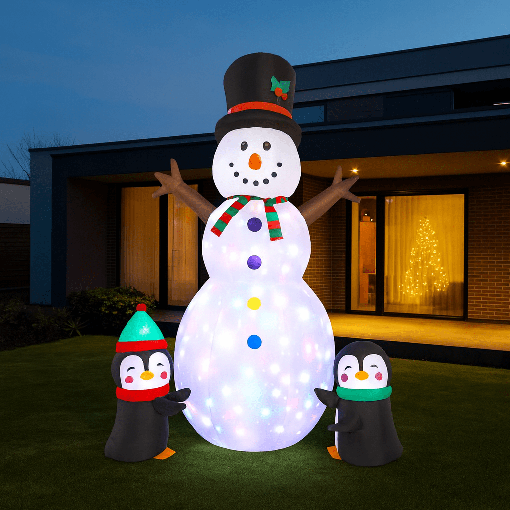 Giant inflatable snowman with illuminated body and penguins in a modern garden at Christmas